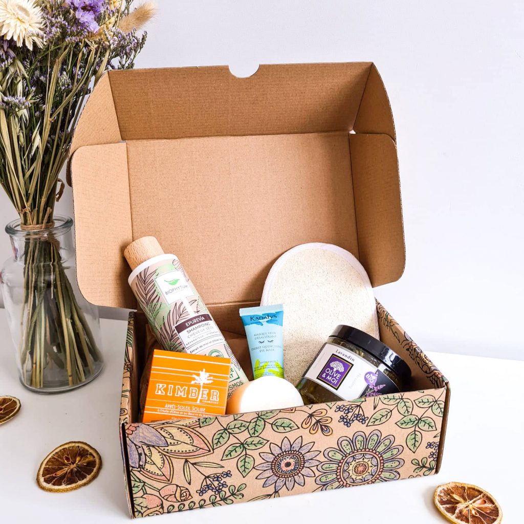 Box ouverte et coloriée contenant 4 produits bio pour la peau et les cheveux et un gant loofah