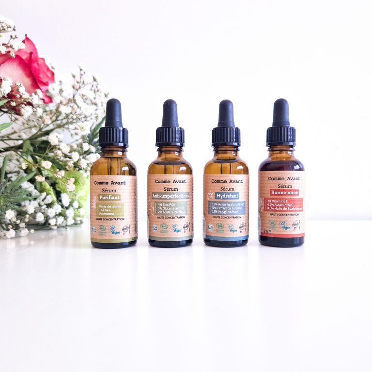 Sérums Comme Avant : mon avis sur ces soins bio hautement concentrés Les 4 sérums bio Comme Avant alignés sur un meuble blanc, avec bouquet de fleurs en arrière-plan soins naturels et made in France